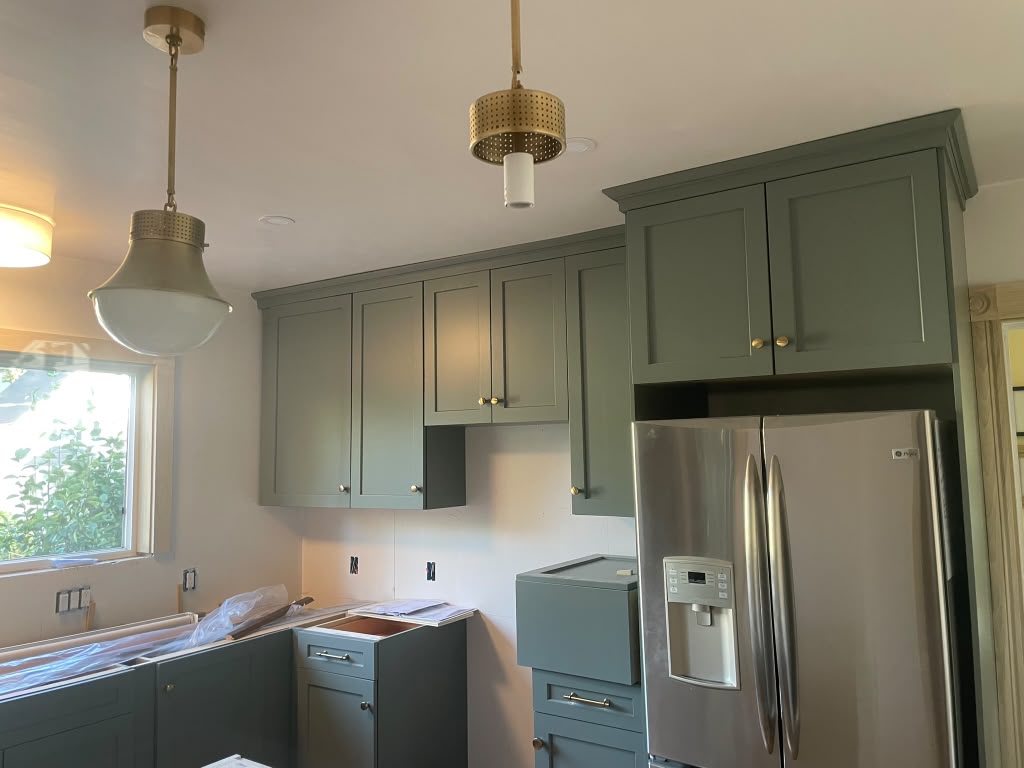 Custom green shaker kitchen cabinet installation with crown molding