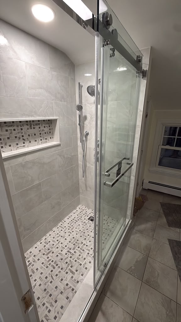 Remodeled bathroom with walk-in tiled shower and glass sliding door